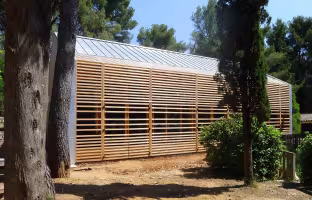 Extension Centre Aéré, façade longue en bois à claire-voie, toiture en zinc, entre les pins