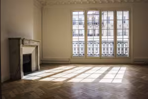 15-17 Canebière, salon vide à cheminée en marbre, parquet en chevrons et porte-fenêtres sur balcon
