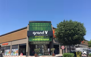 Centre Commercial Grand V, entrée vitrée verte sous l'enseigne Grand V