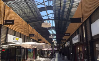 Centre Commercial Grand V, allée couverte d'une verrière à brise-soleils métalliques, avec parasols et boutiques