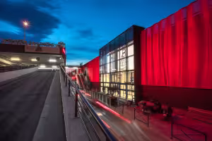 Centre Commercial La Valentine, façade rouge au crépuscule et rampe d'accès