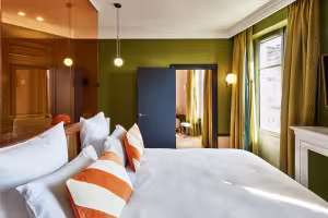 Hôtel de Cambis, chambre aux murs vert olive avec cloison de verre cuivré et coussins orange