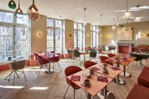 Hôtel de Cambis, salle de petit-déjeuner aux tables rondes, chaises rouges et grandes fenêtres