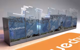 Création de Mobilier Quechua, perspective du comptoir à façade imprimée d'un paysage de montagne et logo orange au sol