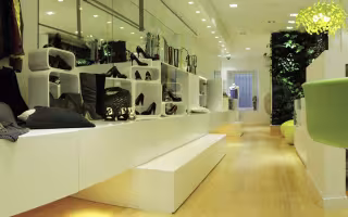 Dolce de Limao Concept Store, gradins blancs présentant des chaussures et sacs, mur végétal au fond
