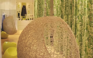 Dolce de Limao Concept Store, fauteuil suspendu en vannerie devant un rideau de feuilles vertes