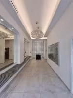 Le Lido Foch, hall d'entrée blanc avec lustre, cloison ajourée rétroéclairée et miroir à motifs