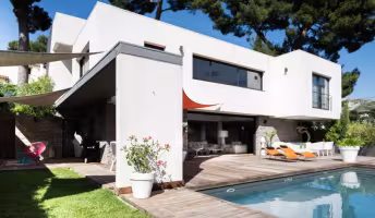 La Panouse, façade sur jardin avec auvent gris, terrasse en bois et mobilier orange