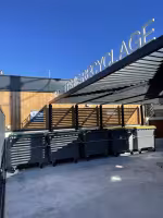 Déchèterie Aire de Carénage Bandol, bacs de déchets alignés sous une pergola à lames, derrière un bardage en bois