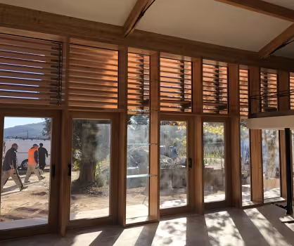 Bastide La Bourrasque, grandes baies vitrées en bois à persiennes vues de l'intérieur