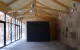 Extension Centre Aéré, grande salle sous charpente en bois, volume noir au centre et façade vitrée sur la gauche