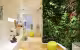 Dolce de Limao Concept Store, mur végétal à côté d'étagères blanches de chaussures et d'un pouf jaune