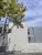 Bureaux SÉRIÈS PEINTURES, mur en béton brut et bardage ondulé gris, branche d'arbre au premier plan